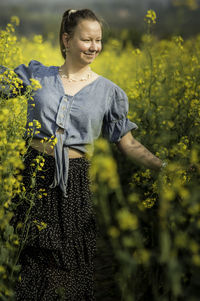 Young woman standing amidst yellow flowers