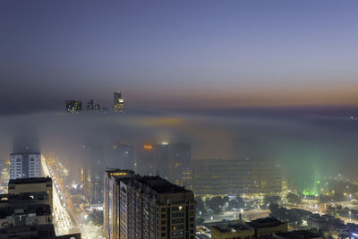 Illuminated buildings in city against sky at night