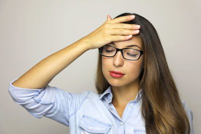 Close-up of woman with headache against gray background