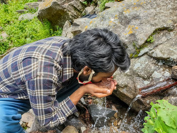 High angle view of man drinking water on rock