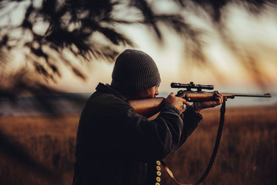 Man aiming rifle on field