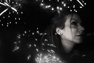 Double exposure image of thoughtful woman and firework display at night