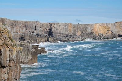 Rock formation by sea against sky