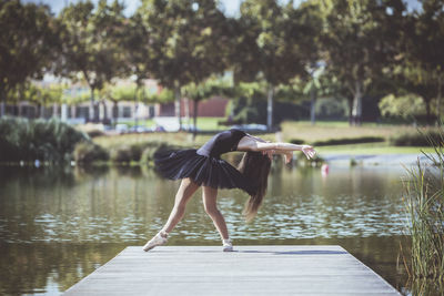 Woman ballet dancing on pier over lake