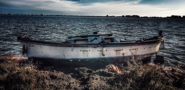 Abandoned boat moored on beach against sky