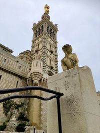 Low angle view of statue against historic building against sky