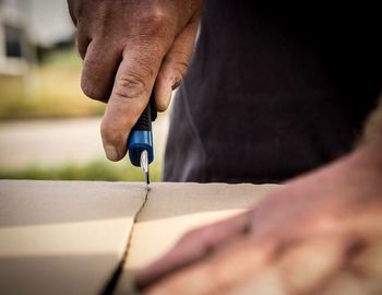 Close-up of man cutting cardboard