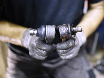 Midsection of mechanic holding car part