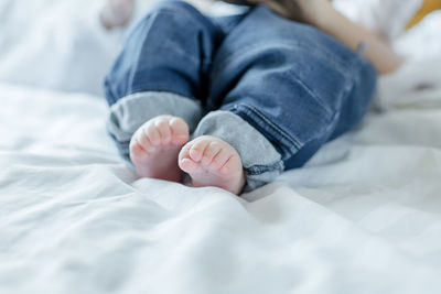 Low section of baby lying on bed