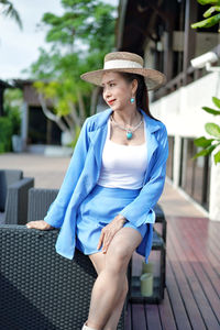 Young woman wearing hat sitting outdoors