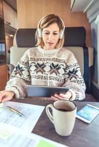 Portrait of young woman using mobile phone while sitting on sofa at home