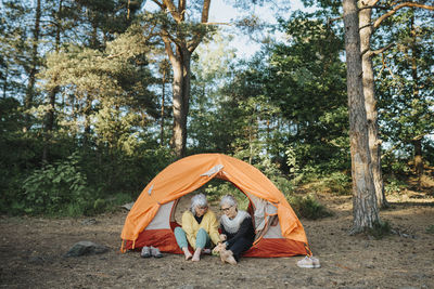 Two senior women sitting in front of tent at campsite