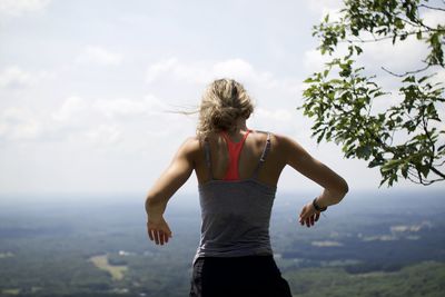 Inspiring rear view of woman standing against sky hope on mountain 