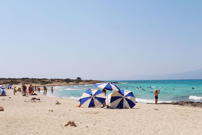 Deck chairs on beach against clear sky