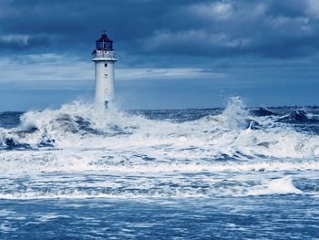 Lighthouse by sea against sky