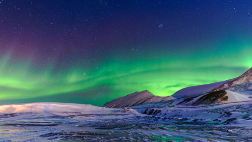 Scenic view of snowcapped mountains against sky at night