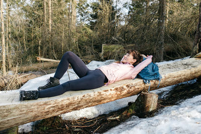 A cute young girl is resting, relaxing lying on a bench in the forest. the traveler took a break 