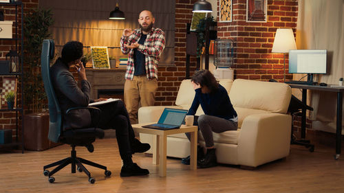 Rear view of woman using digital tablet while sitting on chair at home