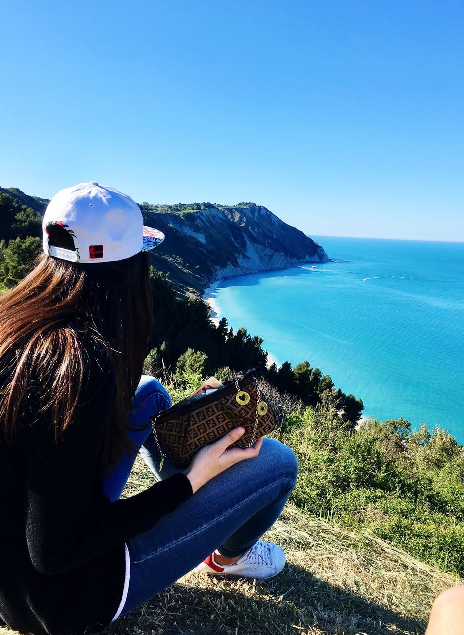 blue, sea, one person, real people, beauty in nature, lifestyles, leisure activity, sky, scenics, outdoors, relaxation, nature, women, water, clear sky, vacations, day, young women, young adult, one young woman only, human body part, people, adult