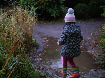 Rear view of  young girl walking into muddy puddle 