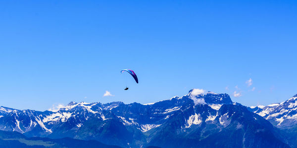 Low angle view of person paragliding against clear blue sky