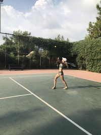 A woman in shorts, a t-shirt and a cap plays tennis. she waved a tennis racket. the ball is batting.