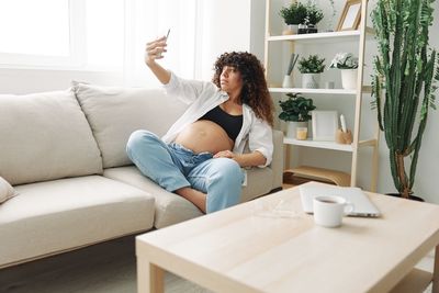 Side view of woman using laptop while sitting on sofa at home