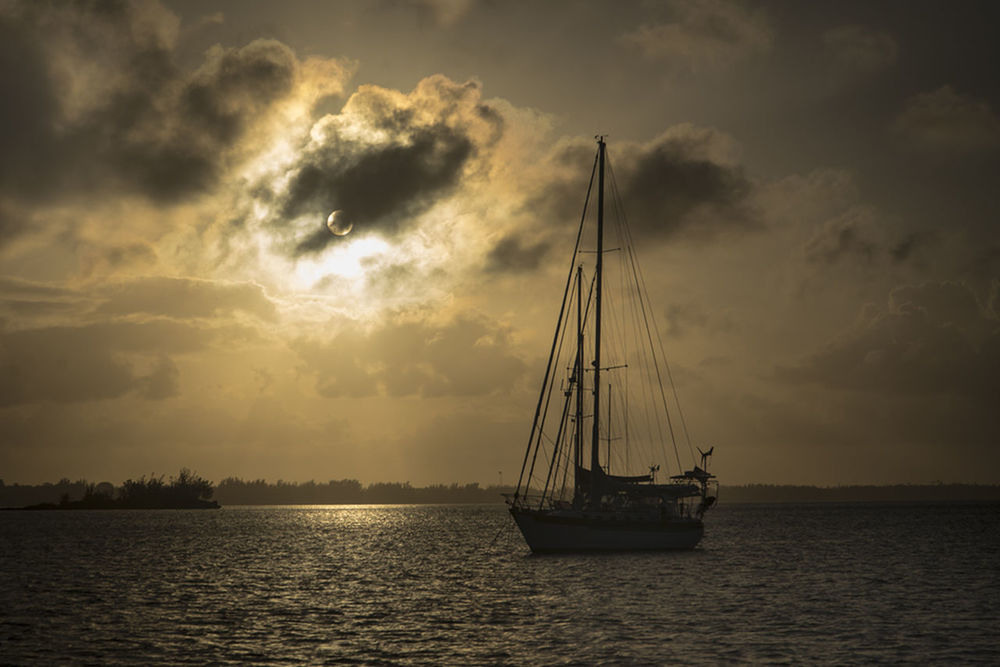 SAILBOAT SAILING IN SEA AT SUNSET