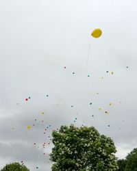 Low angle view of balloons flying against sky