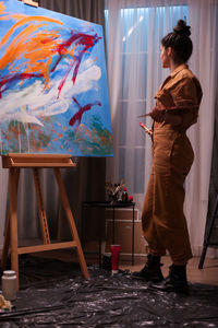 Side view of woman looking at painting at home