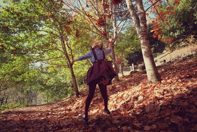 Girl throwing autumn leaves in forest