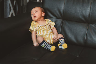 Full length of cute boy sitting at home