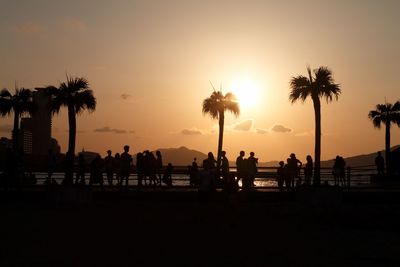 Silhouette people on beach against sky during sunset