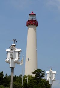 Low angle view of birdhouses and lighthouse against blue sky