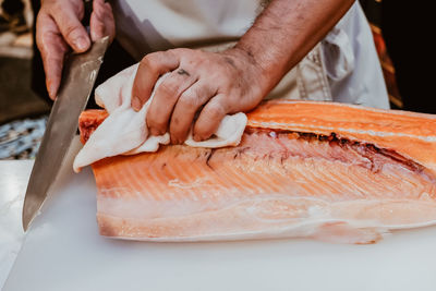 Midsection of man holding fish on table