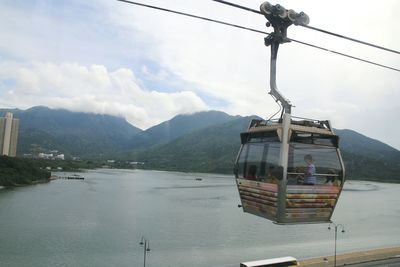 Overhead cable car over lake against sky