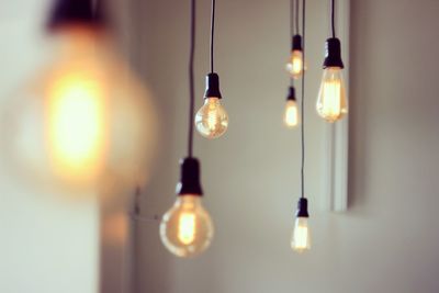 Close-up of illuminated light bulbs hanging at home