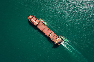  tugboat pulling red oil ship to shipyard dry dock repairing and maintenance in green sea