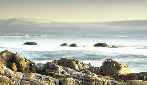 Scenic view of rocks on beach against sky