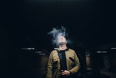 Man smoking while standing in darkroom