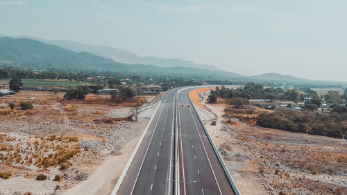 Aerial view of road leading towards mountains against sky