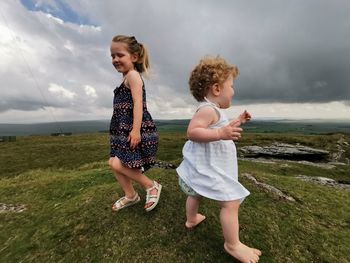 Full length of girls on field against sky 