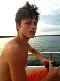 Portrait of young man looking at sea against sky