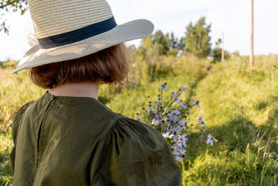 Girl in a linen dress and a straw hat walks . wicker basket in hands. wellness and freedom concept.