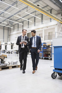 Two businessmen with tablet walking in factory shop floor