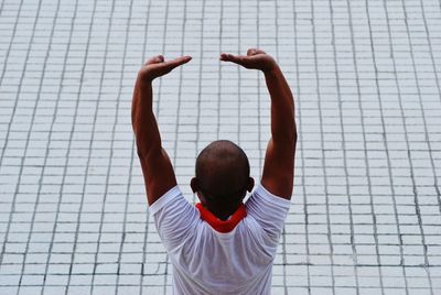 Rear view of man with arms raised standing on footpath