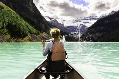 Rear view of woman rowing boat on lake