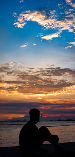 Silhouette man looking at sea against sky during sunset