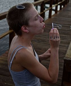 Woman blowing bubbles on wooden pier over sea