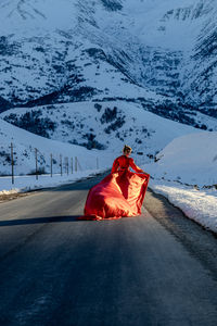 Rear view of woman sitting on snow covered field